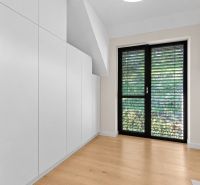 Interior of a family house with built-in wardrobes, a large window, and a floor with a wooden decor.