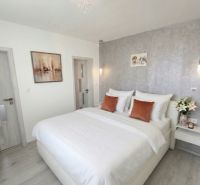 A bedroom in a family house with a wooden decor floor and an elegant bed.