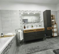 A bathroom in a family house with a large mirror, a bathtub, and decorative tiles.