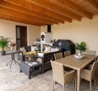 A covered terrace with comfortable rattan furniture in a family house.