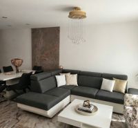 Living room in a family house with a corner sofa, modern table, and stylish chandelier.