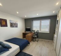 A room in a family house with a computer desk, a bed, and a wooden decor floor.