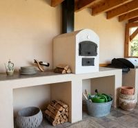 The exterior of a family house in Martin nad Žitavou with an outdoor oven and firewood.
