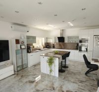 A family house kitchen with a marble floor, a large island, and built-in appliances.
