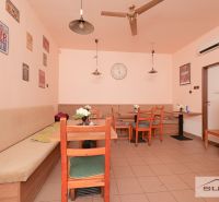 A café with wooden chairs, decorative posters, and a clock on the wall.