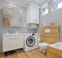 A bathroom in a 4-room apartment with a wooden decor floor and a washing machine.