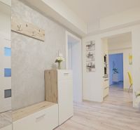 Entrance hallway of a 4-room apartment with a wooden decor floor and white furniture.