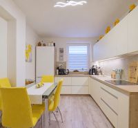 Kitchen in a 4-room apartment, wooden decor flooring, yellow accessories, flower paintings.