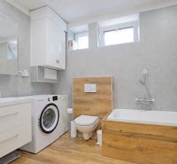 Bathroom in a 4-room apartment with wood-patterned flooring, a washing machine, and a bathtub.