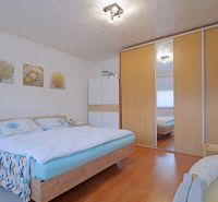 Bedroom with a built-in wardrobe, bed, and floor with wood decor in a 4-room apartment.