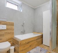 A bathroom with a shower and a bathtub with a wooden decor floor in a 4-room apartment.