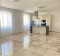 The image shows a spacious kitchen and living room in a three-room apartment on Hlboká Street.