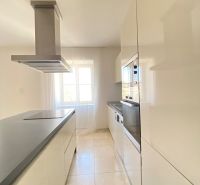 A kitchen in a 3-room apartment with glossy cabinets and a range hood by the window.