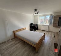 A room in a 4-room apartment with a bed, a table, and a floor with a wooden decor.