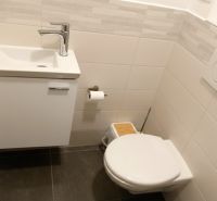 Bathroom in the office with a sink, toilet, and wall tiles.
