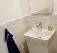 A sink with white tiles, a mirror, and a dark towel in an office.