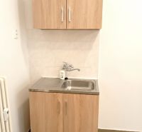 Small kitchen unit with a sink and cabinets, floor with wood decor.