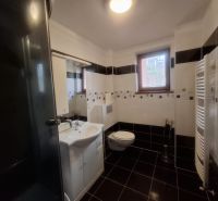Bathroom with a window, shower, sink, and toilet in a family house.
