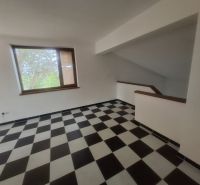 A room in a family house with a window and a staircase, checkered tiles.
