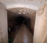 A brick cellar in a family house with stored items on the floor.