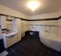 Bathroom with a bathtub, sink, and storage space in a family house.