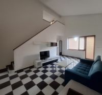 A living room in a family house with a blue sofa and black and white checkered floor.
