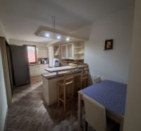A kitchen in a family house with a bar counter, lighting, and a dining table.
