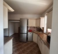 A kitchen in a family house with a wooden decor floor and light furniture.