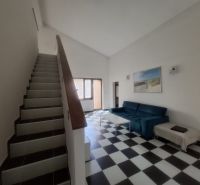 Staircase and living room with black and white flooring in a family house.