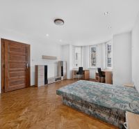 A bright room with a bed, desks, and a wooden-patterned floor.