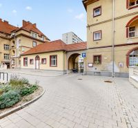Historic buildings with flower beds and a cobblestone path in Nitra, near a 3-room apartment.
