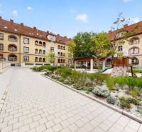 A historic courtyard with greenery and a children's playground in the exterior of a 3-room apartment in Nitra.