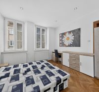 A bright room in a 3-room apartment with a wooden decor floor and a desk.