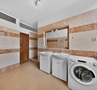 Bathroom with two sinks and a washing machine, tiles with brown decor.