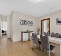 A dining area with wood-patterned flooring connected to the kitchen in a 3-room apartment.