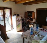 Interior of a cabin with a kitchenette, table, and wooden decor flooring.