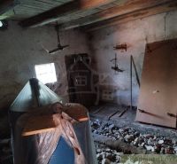 The interior of a cabin with a holey floor, wooden ceiling, and stored materials.