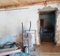 The interior of an old cottage with a cart, a wooden decor floor, and concrete walls.