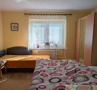 Bedroom in a family house with a bed, armchair, wardrobe, and window sill with decorations.