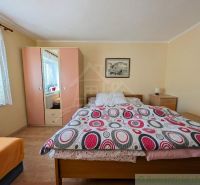 Bedroom in a family house with a bed, a couch, a wardrobe, and wall decorations.