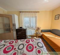 A room in a family house with simple furniture and a colorful bedspread.