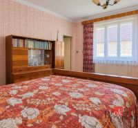 A bedroom in a family house with wooden furniture and a floral bedspread.