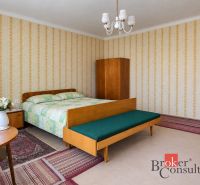 A spacious bedroom with retro furniture, wallpaper, and flowers in a family house.