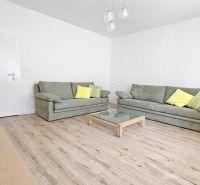 Living room with green sofas, a glass table, and a wooden decor floor.