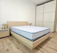 Bedroom with a bed, nightstand, storage wardrobe, and wooden decor flooring in a 2-room apartment.