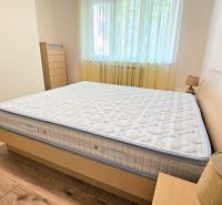 Bedroom in a two-room apartment with a bed and a wooden decor floor.