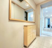 A hallway with a mirror and a wooden dresser in a 2-room apartment.