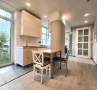 A kitchen in a 2-room apartment with a table and a floor with a wooden decor.