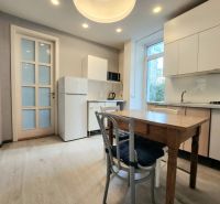 A kitchen in a 2-room apartment with white cabinets and a wood-patterned floor.
