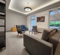 Living room in a two-room apartment with comfortable armchairs, a sofa, and a floor with a wooden decor.